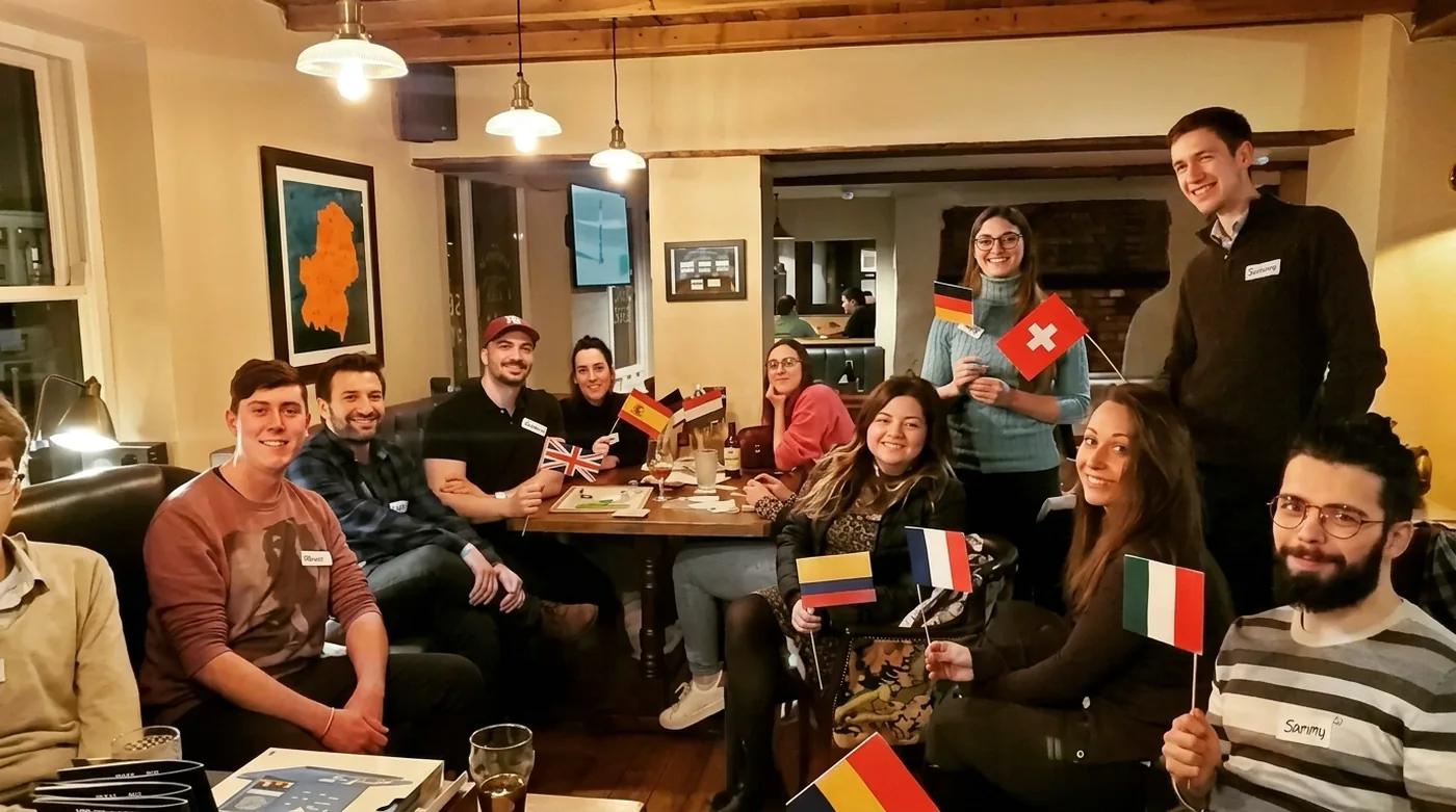 A Guildford Babel evening: a group around a pub table, holding flags of the languages they speak